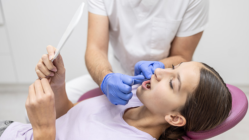 dental hygienist instructing flossing to patient in dental chair